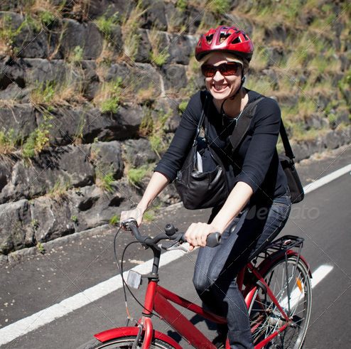 Woman in a red helmet riding a city bike to work
