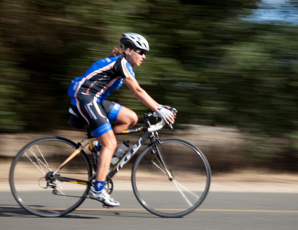 Road cyclist riding fast on a sunny road