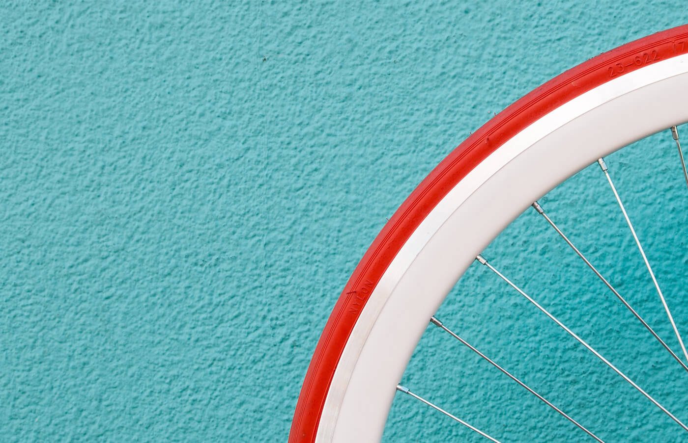 Red bicycle wheel against a turquoise wall